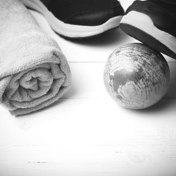 running shoes,towel and earth ball on white wood table concept world healthy black and white tone color style