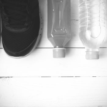 running shoes,drinking water and orange juice on white wood table black and white tone color style