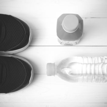 running shoes,drinking water and orange juice on white wood table black and white tone color style