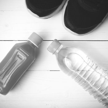 running shoes,drinking water and orange juice on white wood table black and white tone color style