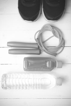 fitness equipment : running shoes,jumping rope,drinking water and orange juice on white wood background black and white tone color style