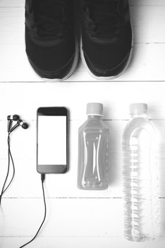 running shoes,orange juice,drinking water and phone on white wood background black and white tone color style