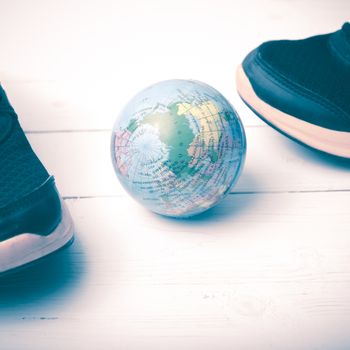 running shoes and earth ball on white wood table concept world healthy vintage style