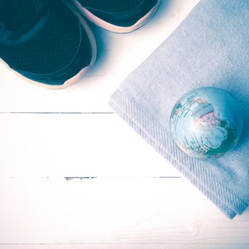 running shoes,towel and earth ball on white wood table concept world healthy vintage style