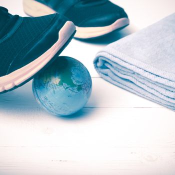 running shoes,towel and earth ball on white wood table concept world healthy vintage style