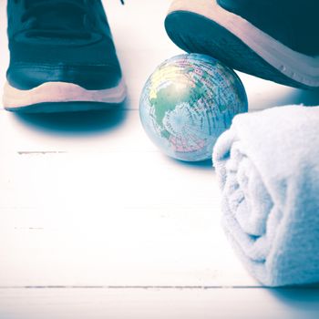 running shoes,towel and earth ball on white wood table concept world healthy vintage style