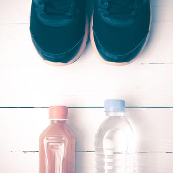 running shoes,drinking water and orange juice on white wood table vintage tone color style