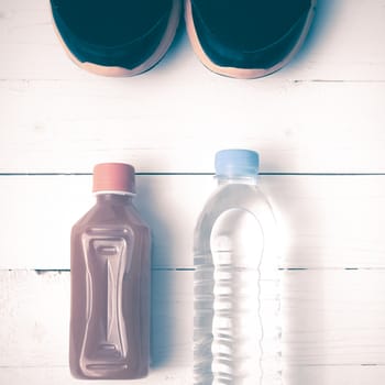 running shoes,drinking water and orange juice on white wood table vintage tone color style