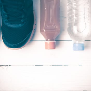 running shoes,drinking water and orange juice on white wood table vintage tone color style