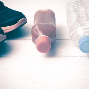 running shoes,drinking water and orange juice on white wood table vintage tone color style