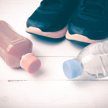 running shoes,drinking water and orange juice on white wood table vintage tone color style