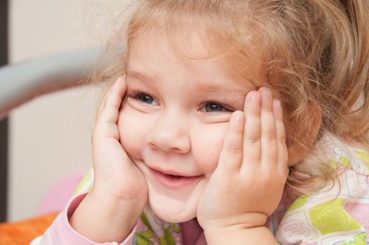 Cheerful three year old girl lying on the bed and looked to the left