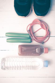 fitness equipment : running shoes,jumping rope,drinking water and orange juice on white wood background vintage tone style