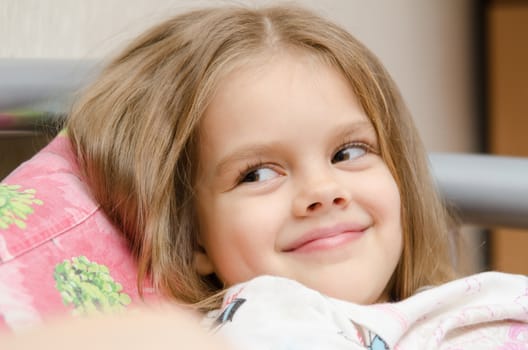 Cheerful five year old girl lying on the bed and looked left smorit