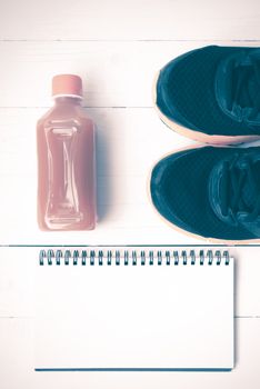 running shoes,orange juice and notepad on white wood background vintage tone color style