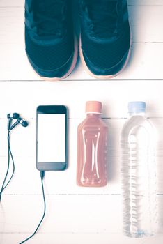 running shoes,orange juice,drinking water and phone on white wood background vintage tone color style