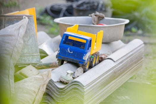 Old toy truck lay on a pile of slate in the street at village house