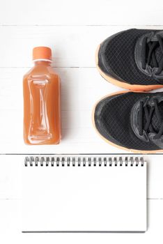running shoes,orange juice and notepad on white wood background