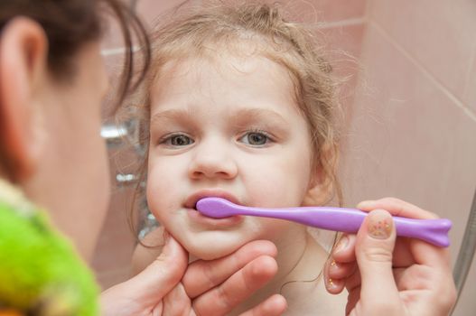 Mom helps his three-year daughter brushing teeth