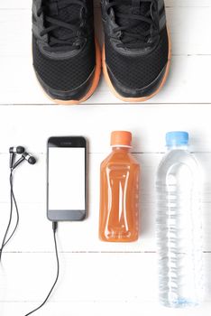running shoes,orange juice,drinking water and phone on white wood background