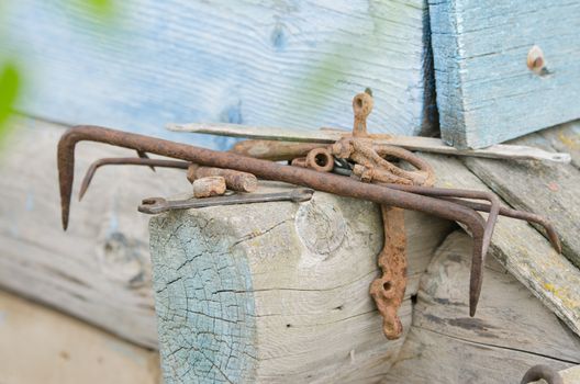 Pile of old tools and pieces of iron lying on the wooden frame of the old village house