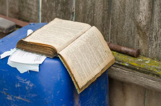 Solodniki, Russia - May 13, 2015: The old open book lying on a barrel at the rustic fence