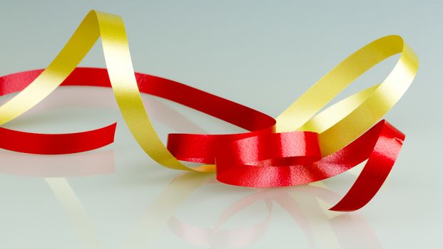 Gold and Red Ribbon String close up on grey/white background.