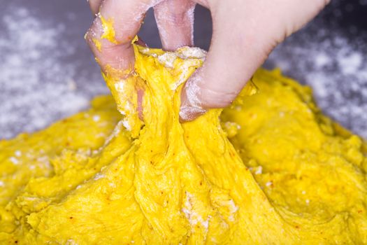 Hand in Saffron Bun Dough close up image.