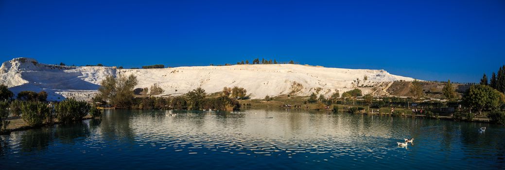 Panoramic view of white hill in Pamukkale and pools on clear sky background, Denizli, Turkey.