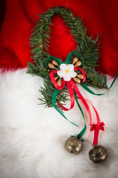 Christmas garland and small bells on red and white fur with dark vignette