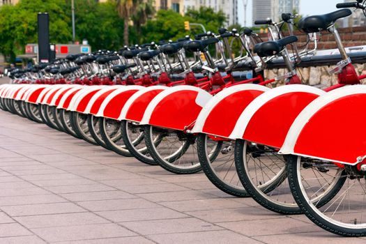 Long row of red and white bicycles (public bikes) near the harbor in Ronda Litoral, Barcelona - Spain