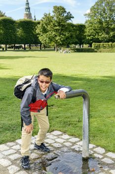 Boy getting a much needed drink from a water fountain in a park.