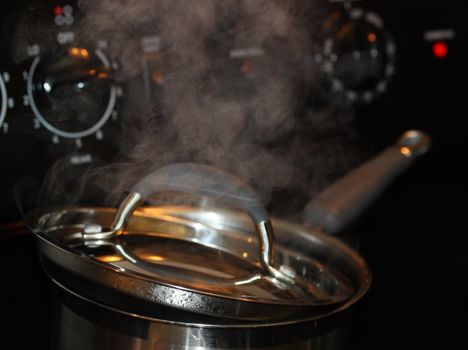 Steam coming out of boiling pot on the hot stove.
