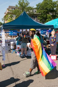 Nyack, NY, USA - June 14, 2015: During Rockland Pride Hillary Clinton from photo on silhouette watching man with LGBT flag, both smiling.