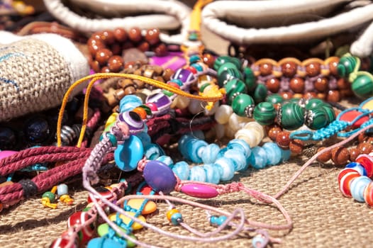 Different bright, multi-colored jewelry of handwork in a sunlight