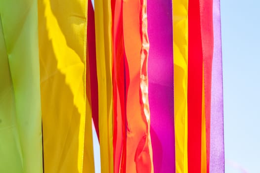 Multi-colored strips of tapes on a wind in the sunny summer day