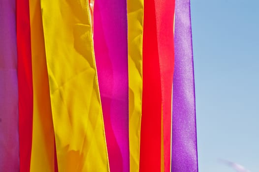 Multi-colored strips of tapes on a wind in the sunny summer day