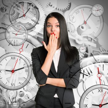 Surprised businesswoman on abstract background with clocks