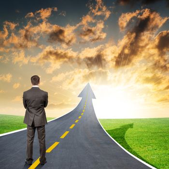 Businessman standing on highway road going up as an arrow in sky