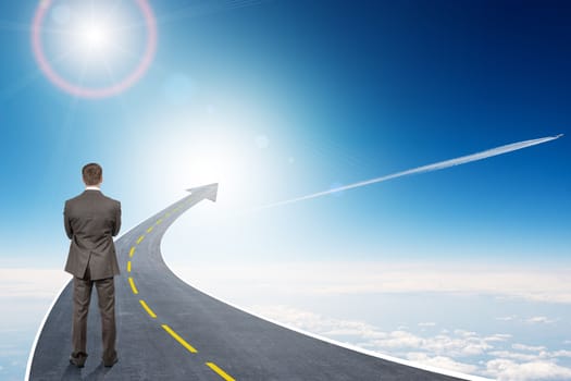 Businessman standing on highway road going up as an arrow in sky