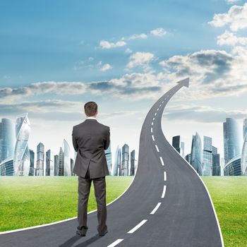 Businessman standing on freeway road going up as an arrow in sky