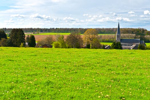 Green Meadow on the Background of the Village Church in Belgium