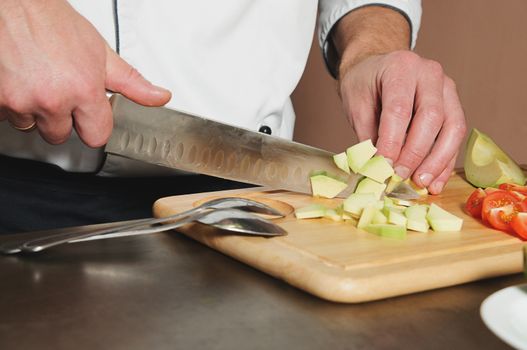 chef cutting avocado on table with knife