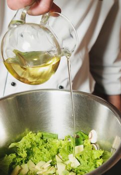 chef adding oil in vegetarian salad