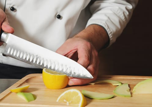 chef cutting lemon on table with knife