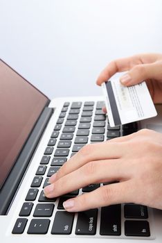 Vertical picture of Human next to laptop with credit card on white background