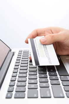 Vertical shot of Human next to laptop with credit card on white background