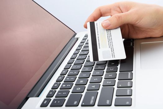horizontal shot of  Human next to laptop with credit card on white background