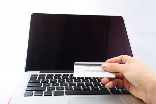 view from eye level of Human next to laptop with credit card on white background