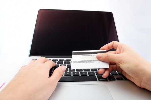 view from eye level of Human next to laptop with credit card on white background